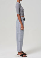 Person wearing light gray cargo pants and a cropped top on a white background