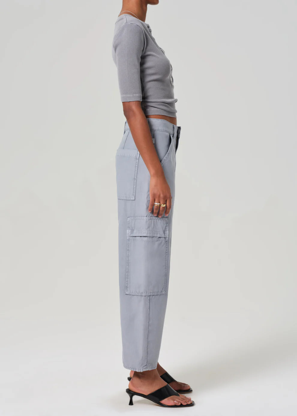 Person wearing light gray cargo pants and a cropped top on a white background