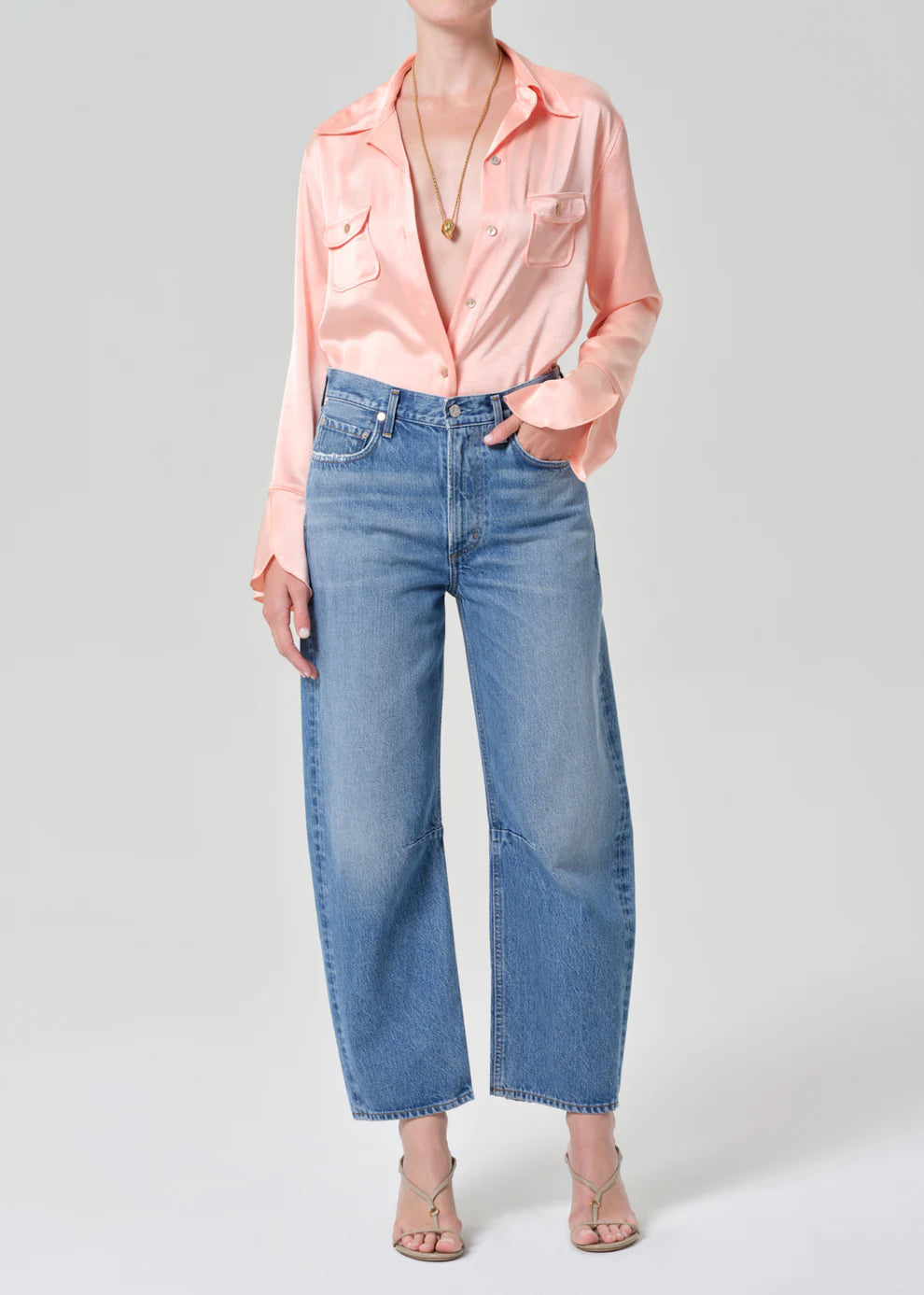 Person wearing a pink blouse and blue jeans on a white background