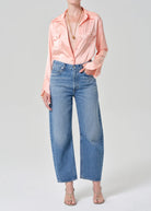 Person wearing a pink blouse and blue jeans on a white background