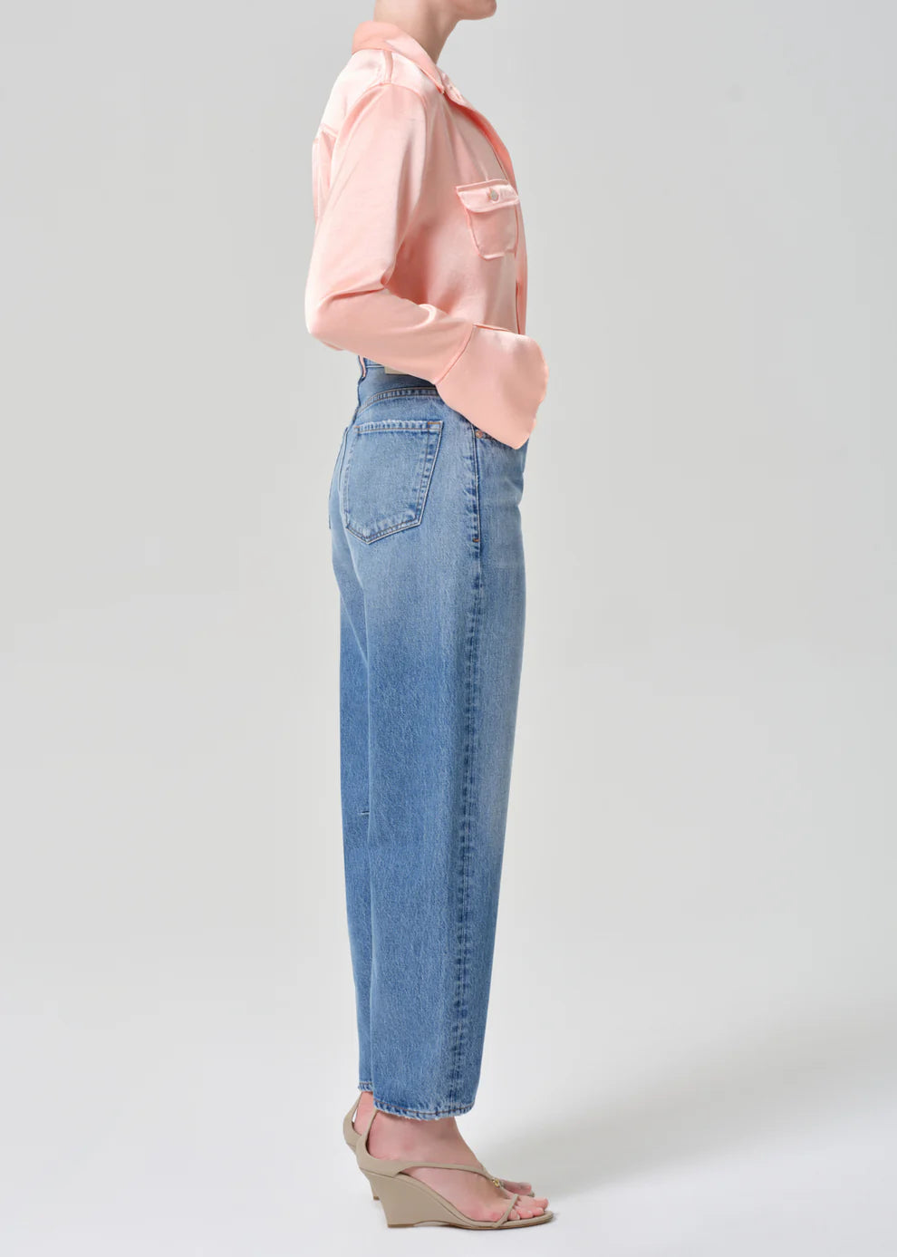 Person wearing a light pink blouse and blue jeans on a white background