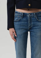 Person wearing blue jeans with a plain background