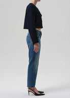 Person wearing a black cropped top and blue jeans on a white background