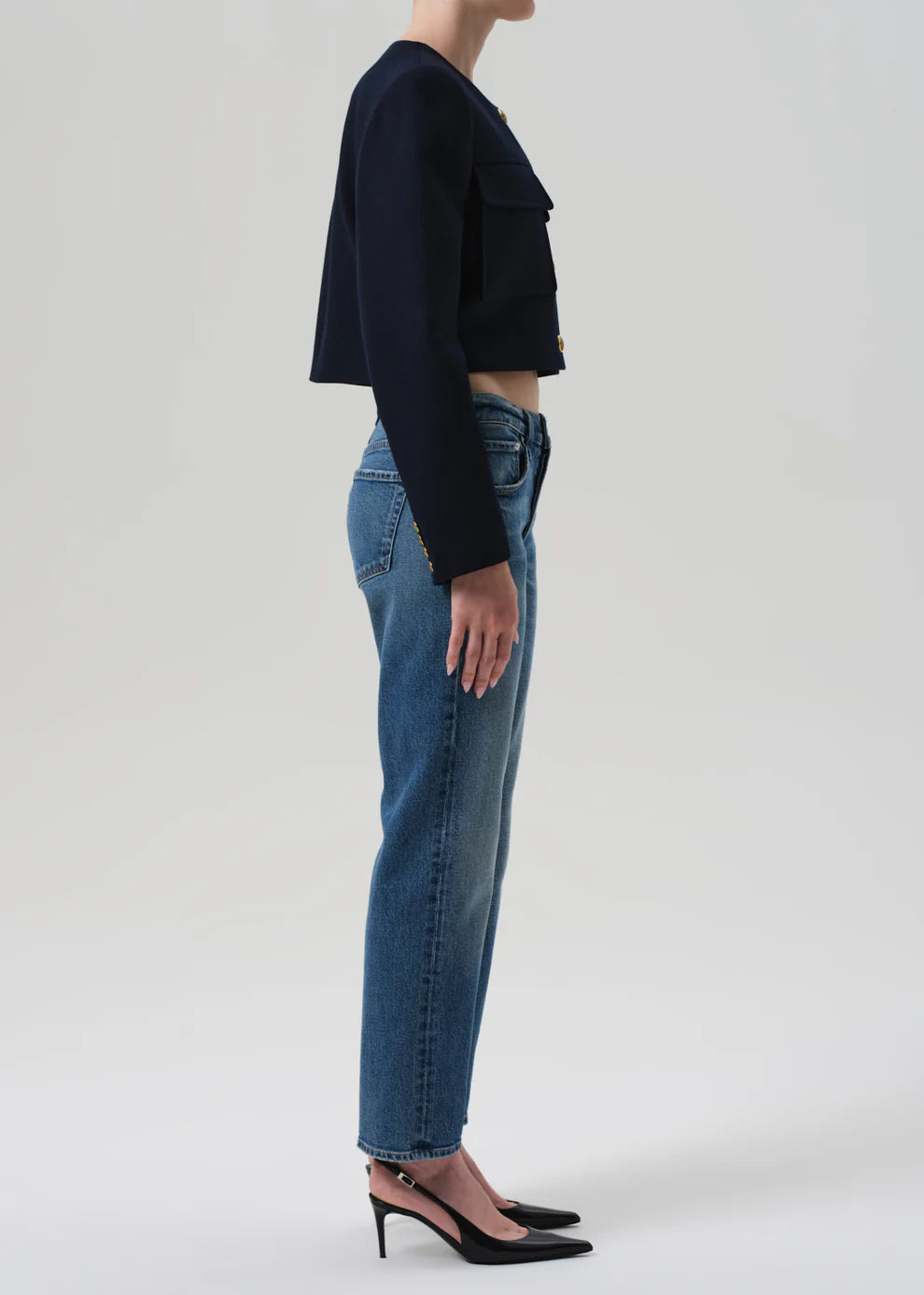 Person wearing a black cropped top and blue jeans on a white background
