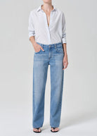 Person wearing a light blue shirt and jeans on a white background