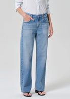 Person wearing light blue jeans and a white shirt on a plain background