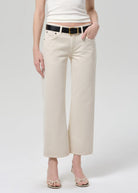 Person wearing beige wide-leg pants with a white top on a plain background