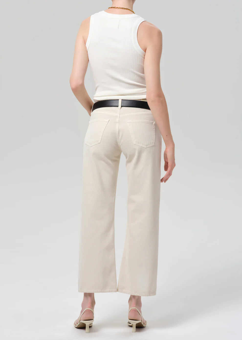 Person wearing a white sleeveless top and beige wide-leg pants on a light gray background
