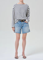 Person wearing a striped shirt and denim shorts on a white background