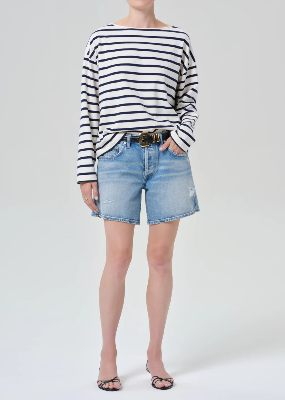 Person wearing a striped shirt and denim shorts on a white background