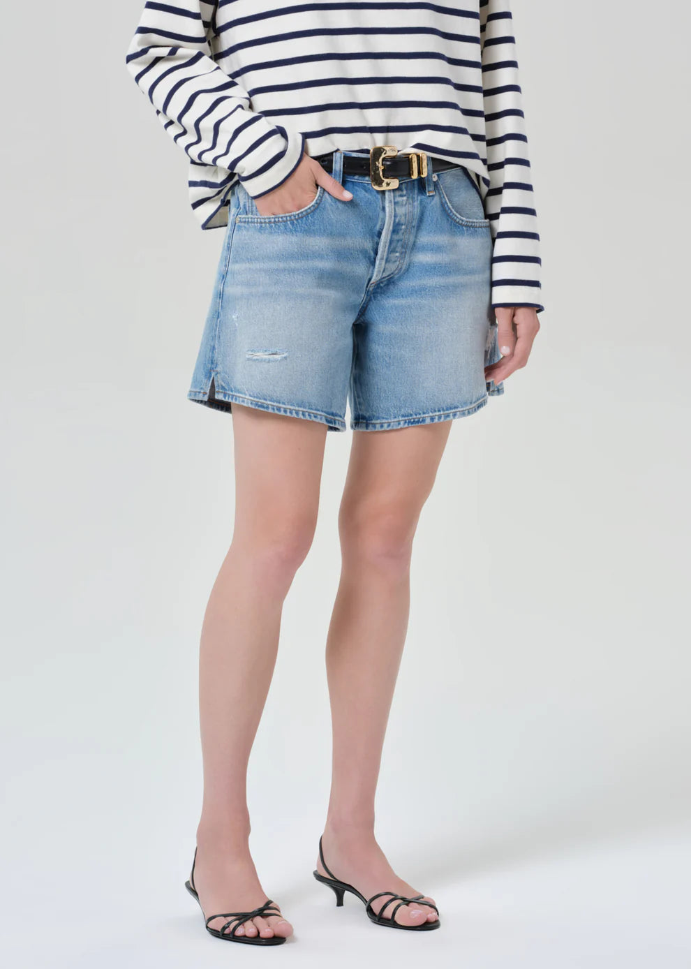 Person wearing a striped shirt and denim shorts on a white background