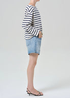Person wearing a striped sweater and denim shorts on a plain background