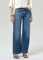 Person wearing blue jeans and a white shirt on a plain background