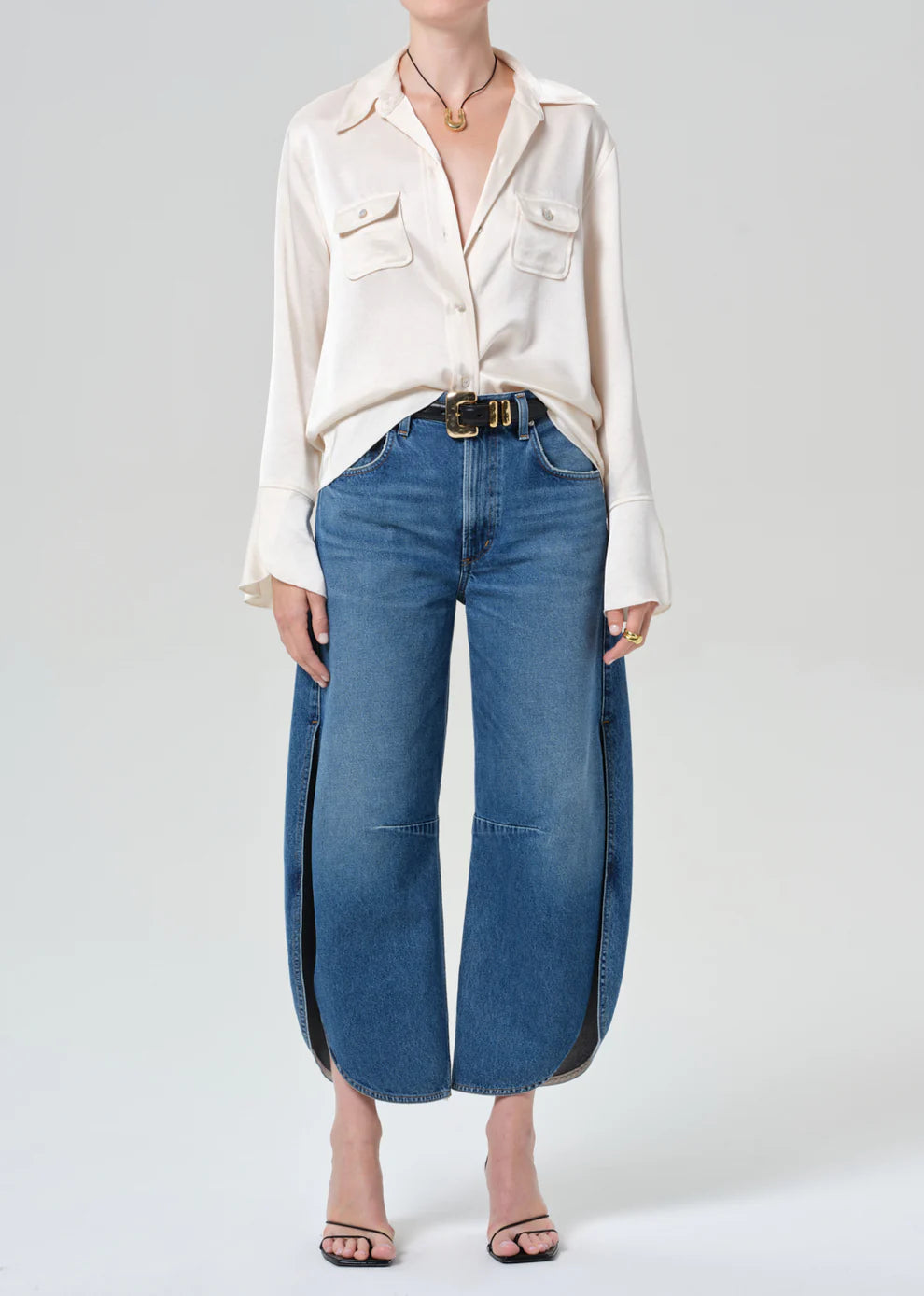 Person wearing a white blouse and blue jeans on a plain background