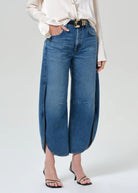 Person wearing blue wide-leg jeans on a plain background