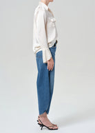 Person wearing a white blouse and blue jeans on a plain background