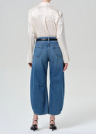 Person wearing a white shirt and blue jeans on a plain background