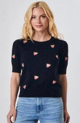 Woman wearing a black sweater with pink floral patterns on a white background