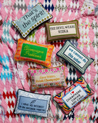 Colorful embroidered pillows with humorous sayings on a patterned fabric background