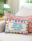 Decorative pillow with nautical flags and text on a couch