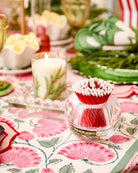 Decorative table setting with a candle, matches, and floral tablecloth.