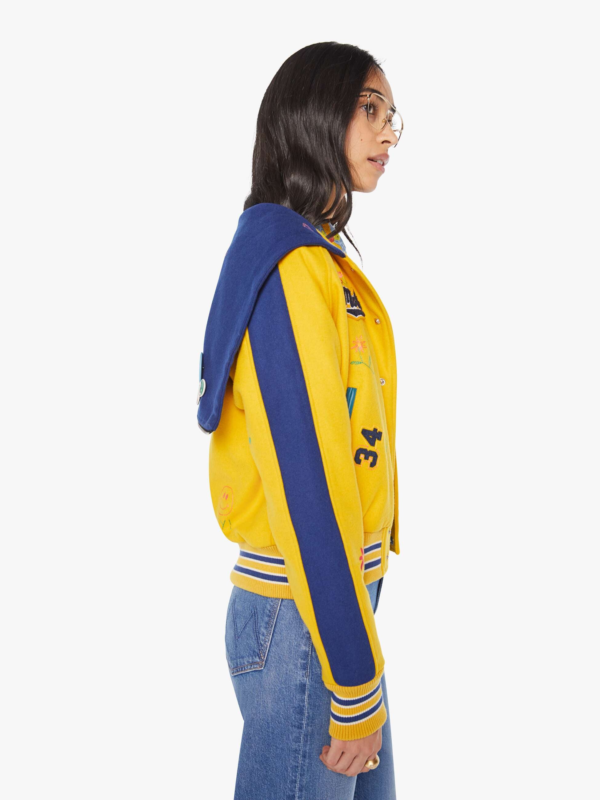Person wearing a yellow and blue varsity jacket with number 34 on a white background