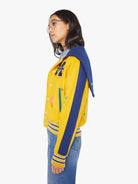 Person wearing a yellow and blue jacket with colorful designs on a white background