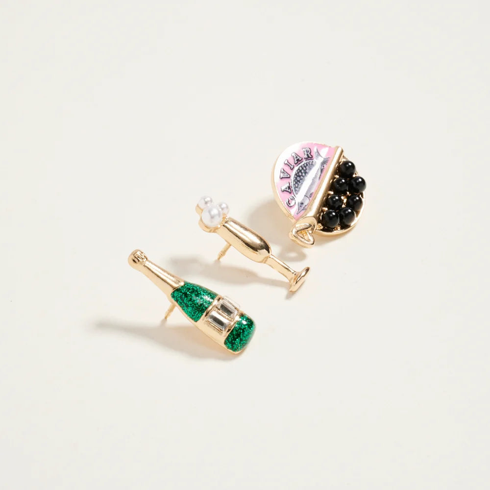 Champagne bottle-shaped earrings with green gemstones on a light background