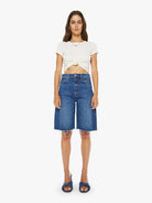 Woman wearing a white top and blue denim shorts on a white background