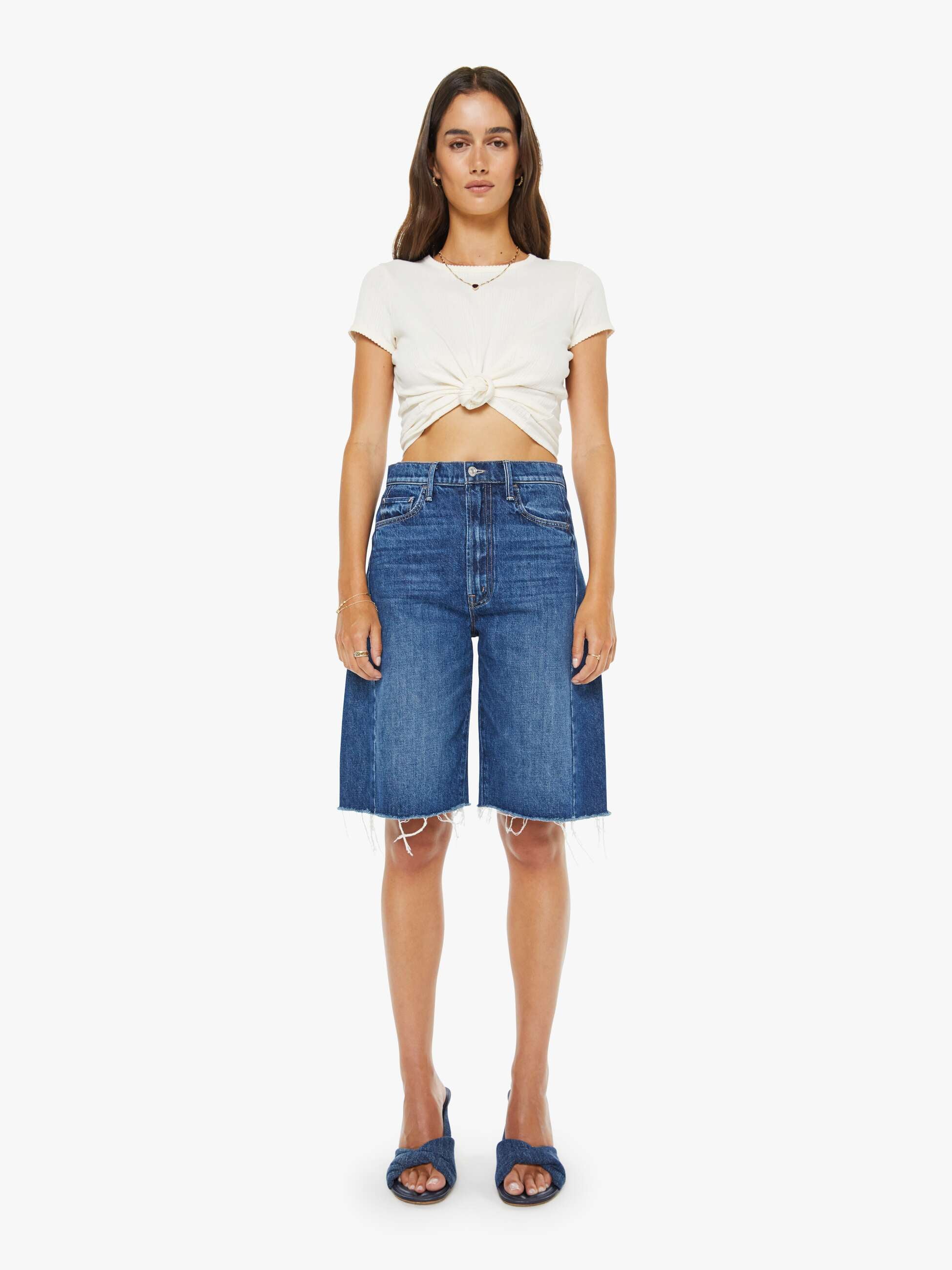 Woman wearing a white top and blue denim shorts on a white background
