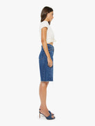 Woman wearing a white top and blue denim skirt on a white background