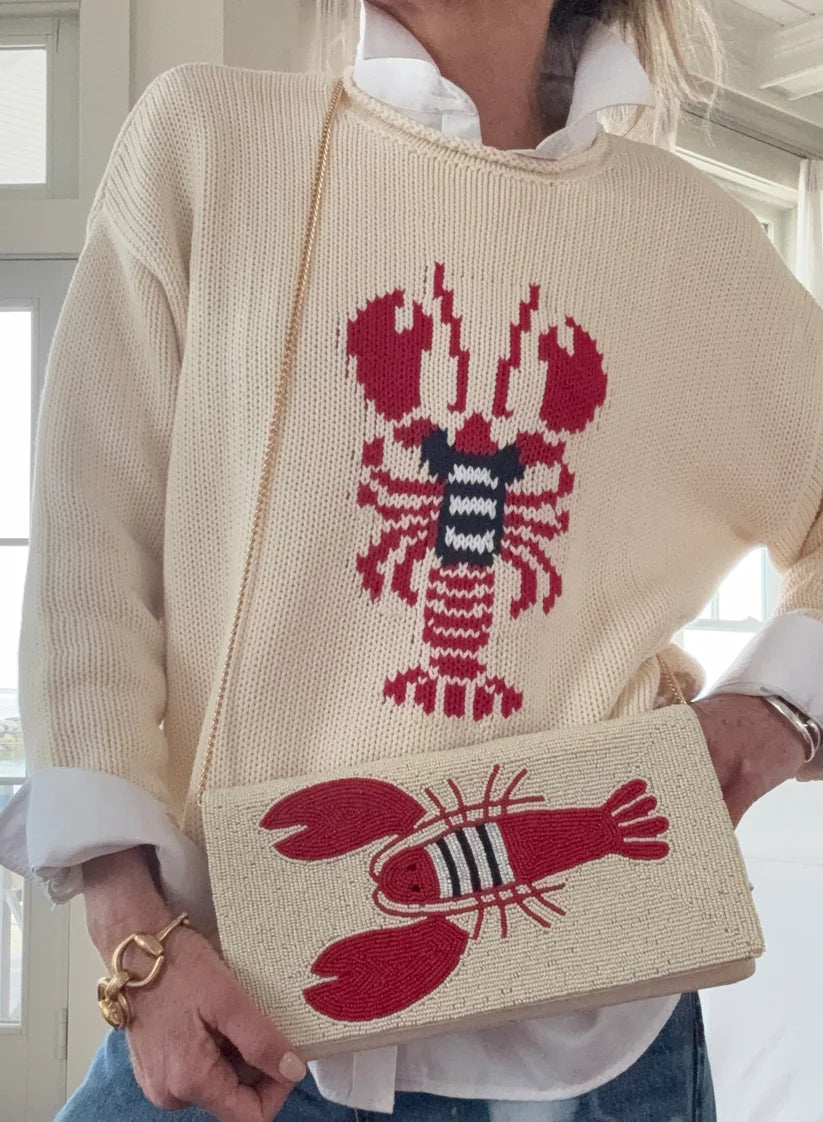Person wearing a sweater with a lobster design, holding a matching handbag.