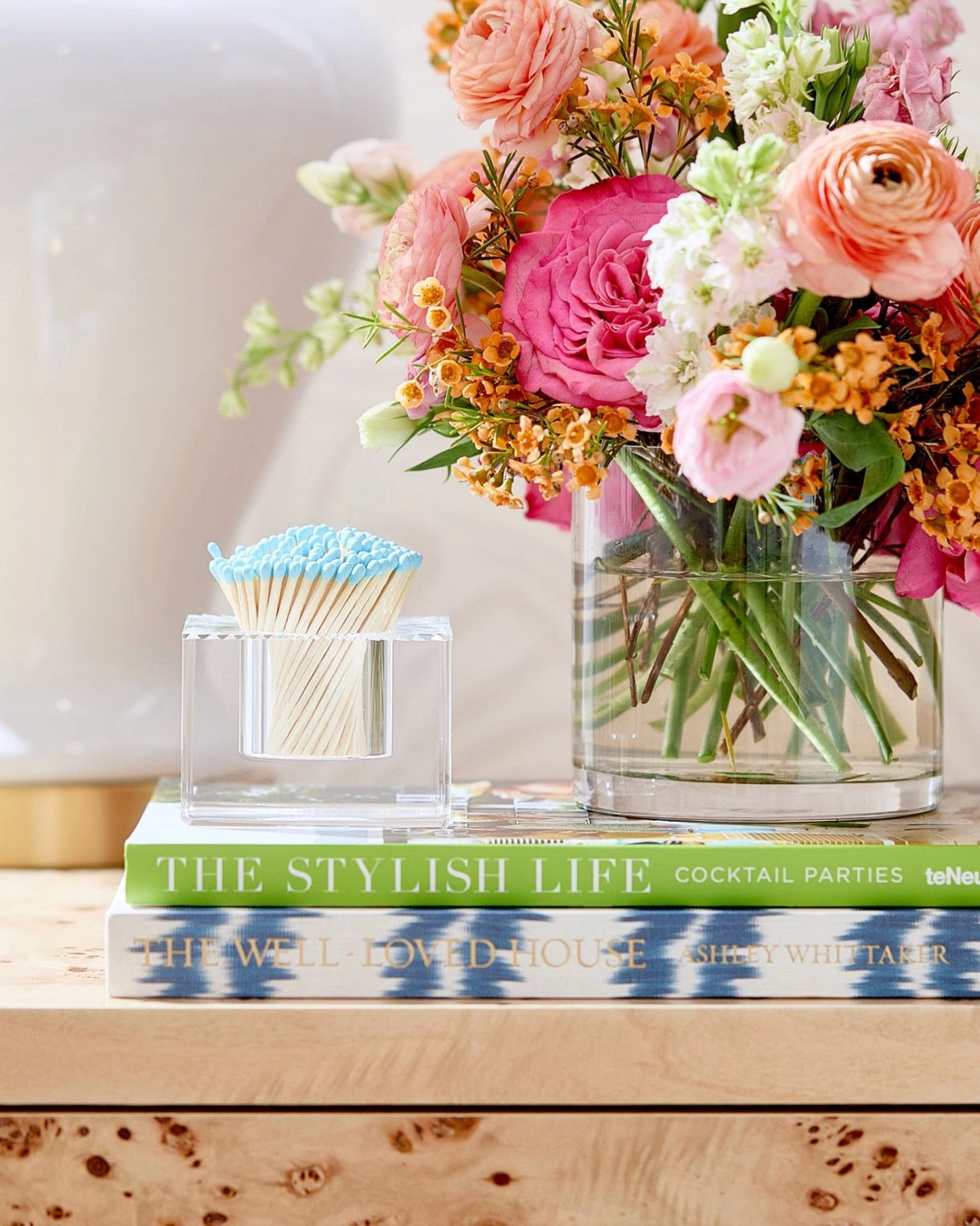Vase with flowers, books, and a toothpick holder on a wooden surface