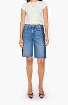 Person wearing a white top and blue denim shorts on a white background