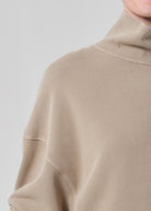 Close-up of a beige sweater with a high collar on a light gray background