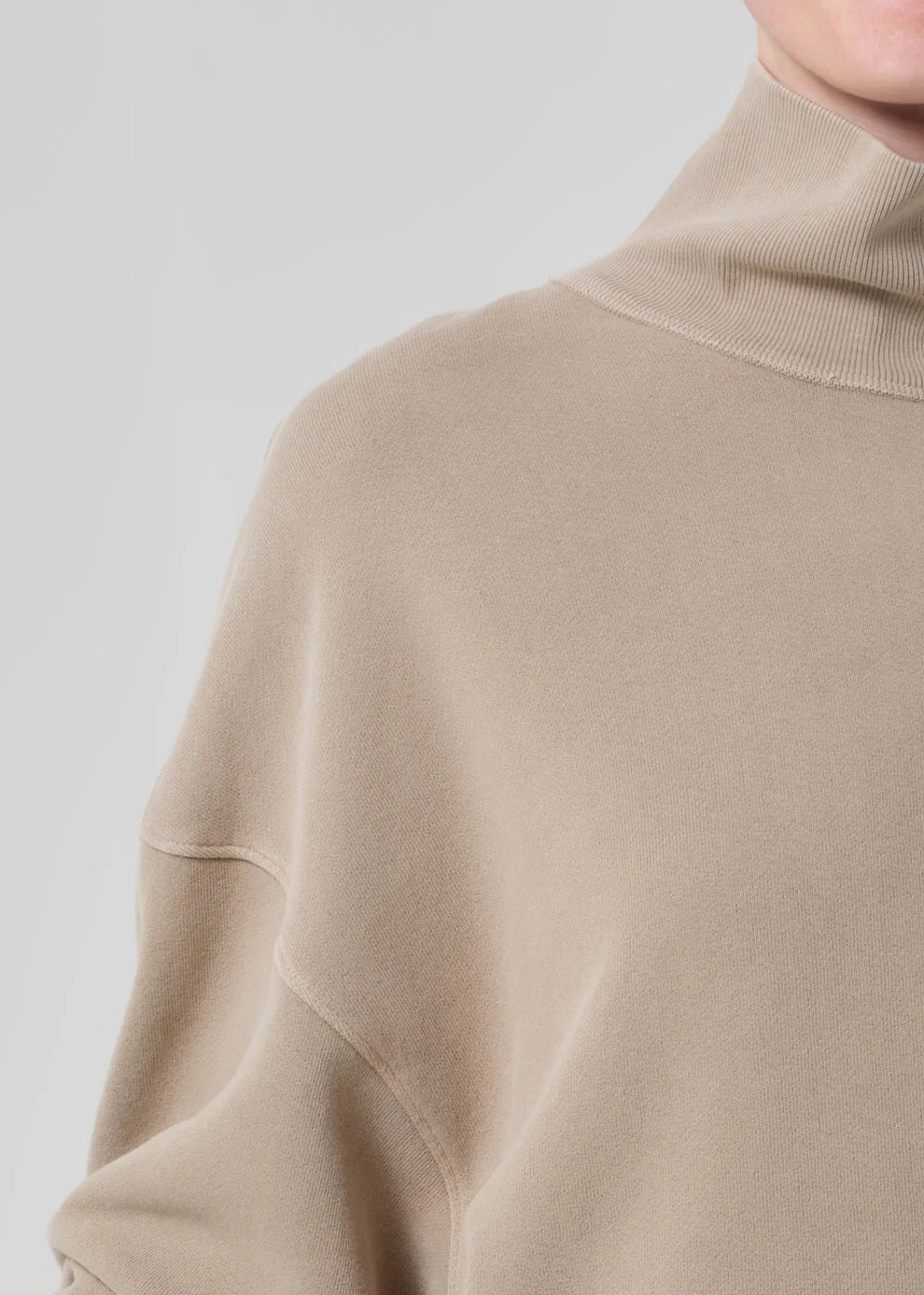 Close-up of a beige sweater with a high collar on a light gray background