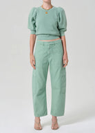 Person wearing a mint green outfit with a top and pants on a white background