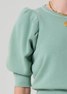 Light green sweatshirt worn by a person on a plain background