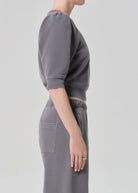 Person wearing a gray sweatshirt and pants on a light gray background