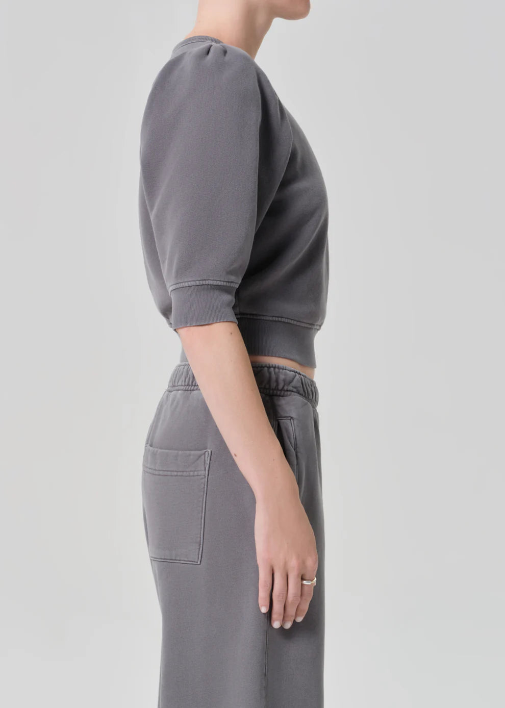 Person wearing a gray sweatshirt and pants on a light gray background