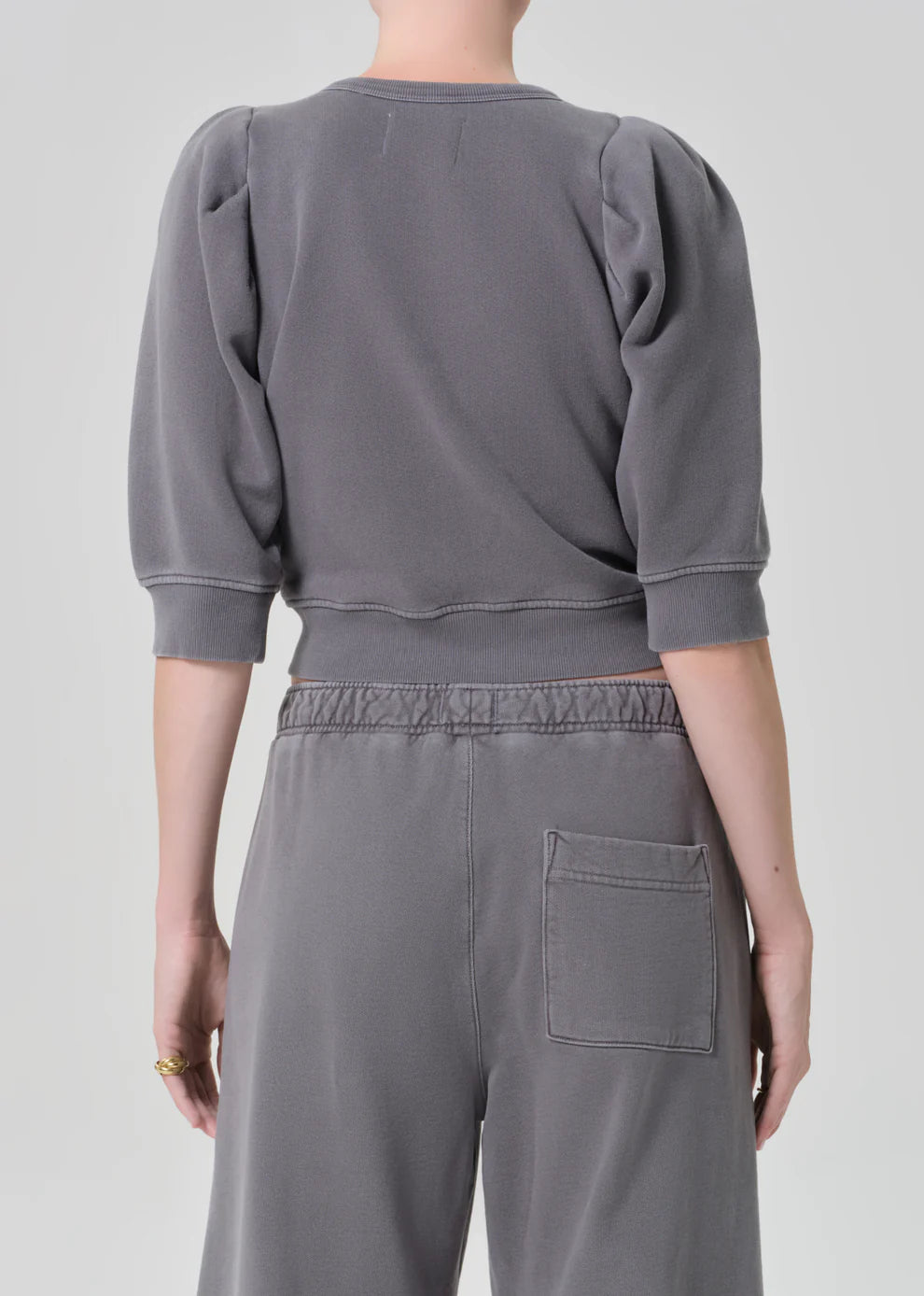 Person wearing a gray sweatshirt and pants on a plain background