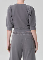 Person wearing a gray sweatshirt and pants on a plain background