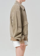 Person wearing a beige jacket on a plain background