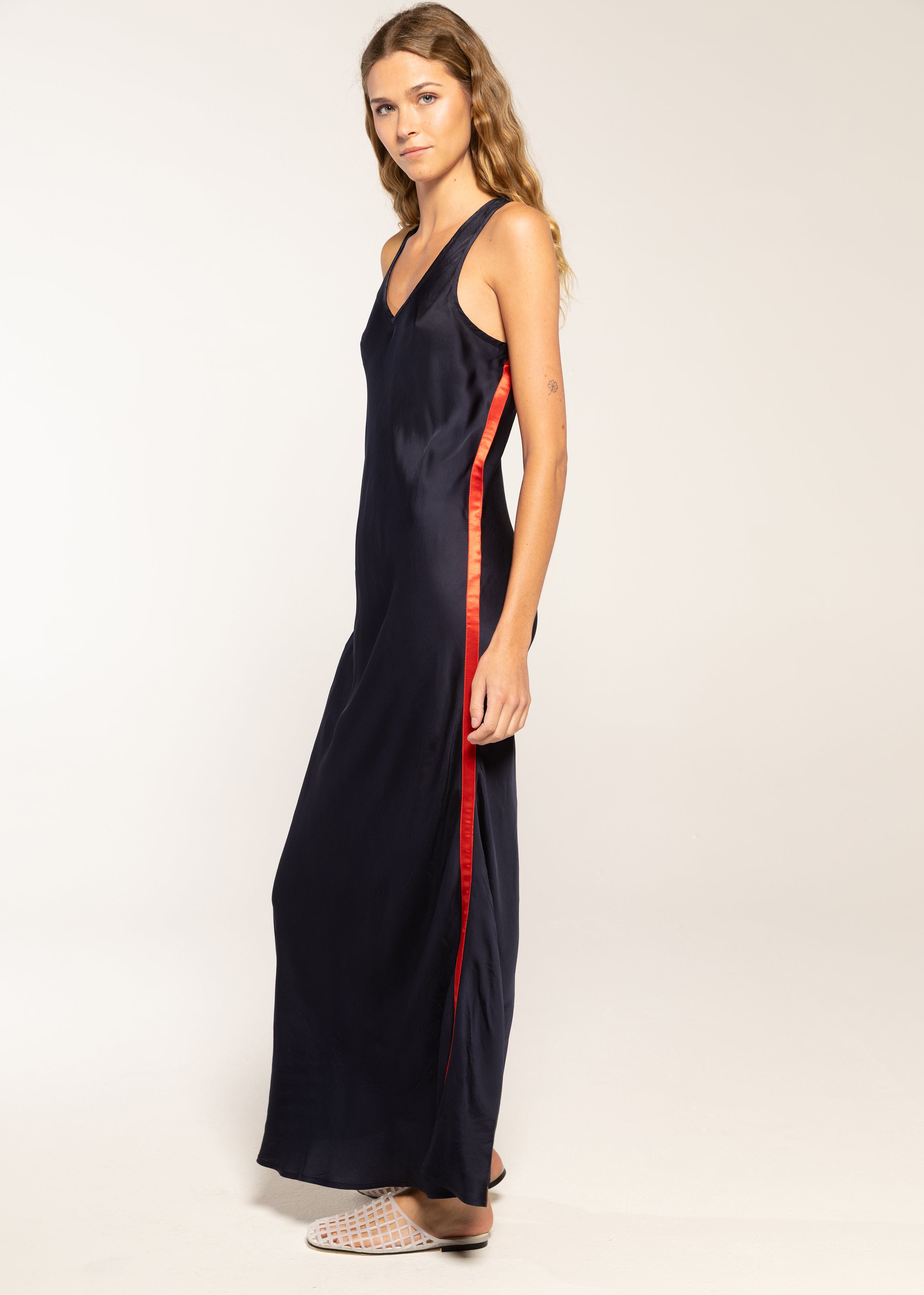 Woman wearing a long navy dress with a red stripe on a white background