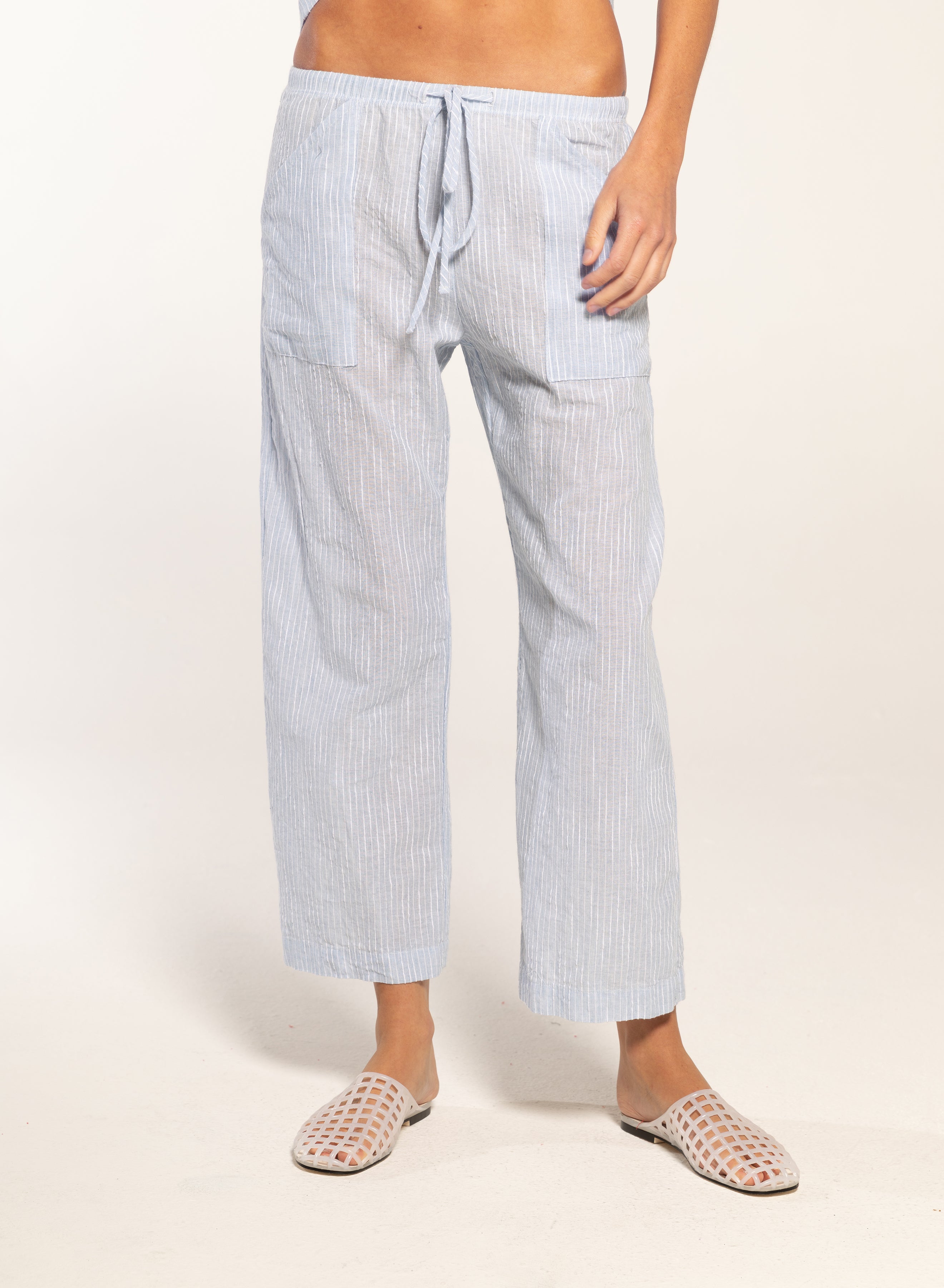 Person wearing light blue striped pajama pants on a white background