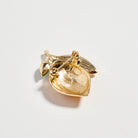 Gold leaf-shaped brooch on a light gray background