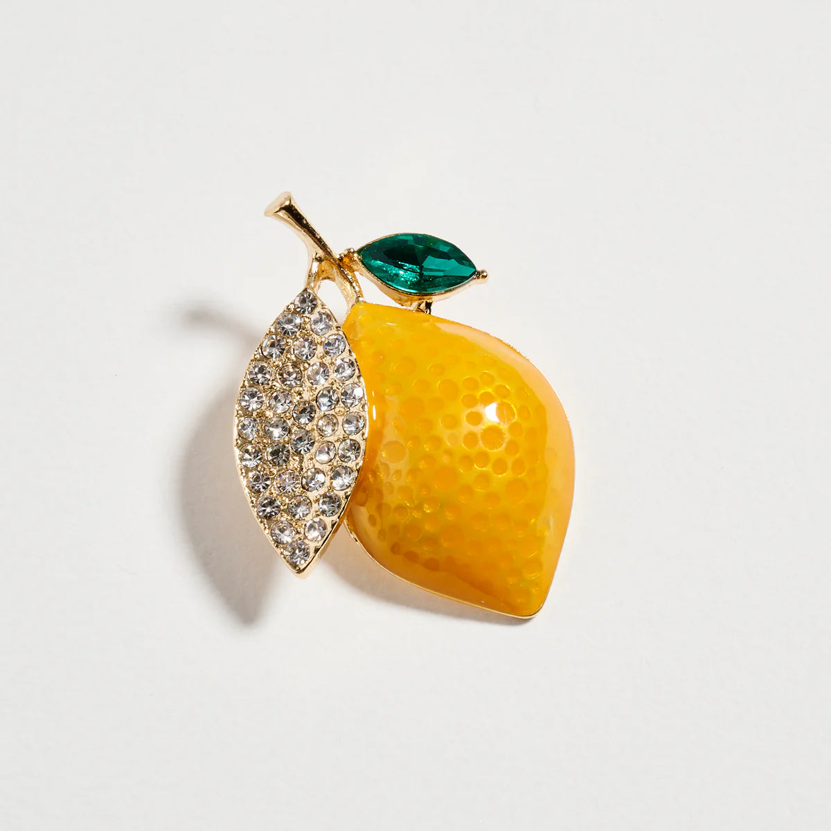 Lemon-shaped brooch with gemstone details on a light gray background