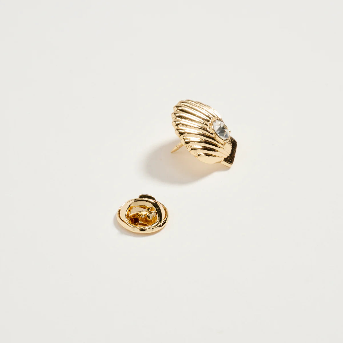 Gold shell-shaped earring on a light gray background