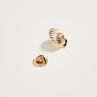 Gold shell-shaped earring on a light gray background