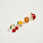 Fruit-themed earrings on a light gray background